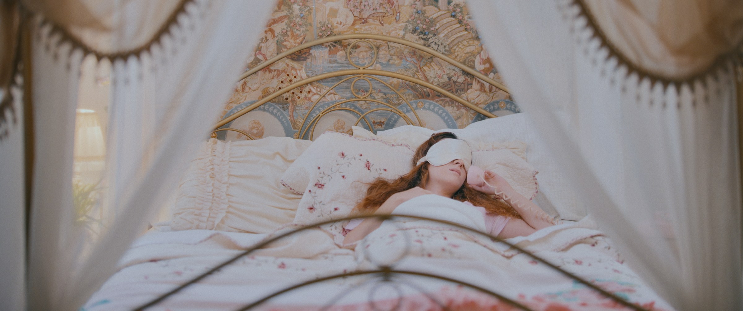 GLIMMR – Woman asleep in canopy bed holding pink phone